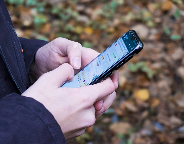 Una persona con el celular en la mano enviando un mensaje